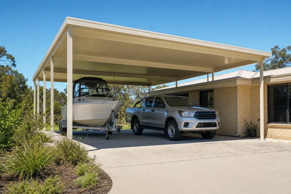 Extra-high flat roof carport over a boat on a trailer beside a brick home