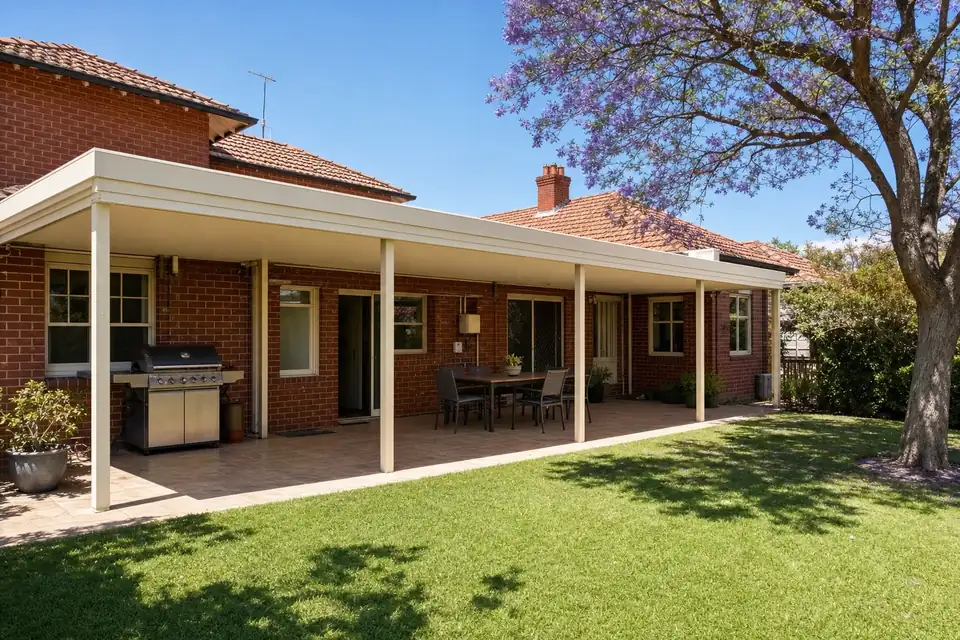 Wide cream flat roof patio along the back of a red brick Perth home with a barbecue area