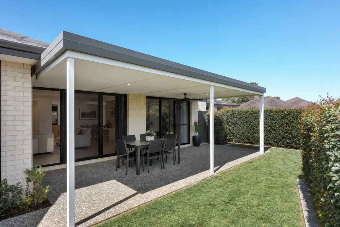 Flat roof patio with a grey edge, white posts and a white ceiling with downlights over outdoor dining