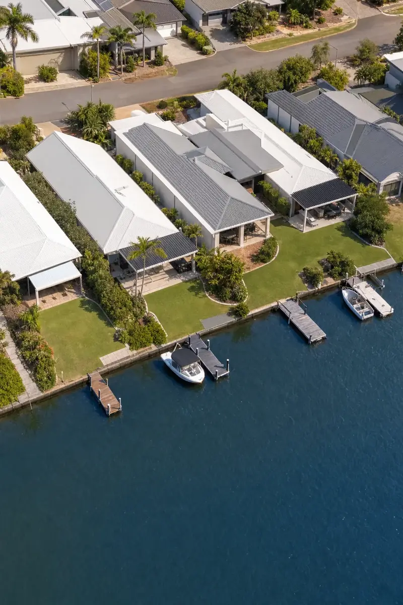 Aerial view of canal homes with steel patios over their back alfrescos, and boats at the jetties on the water