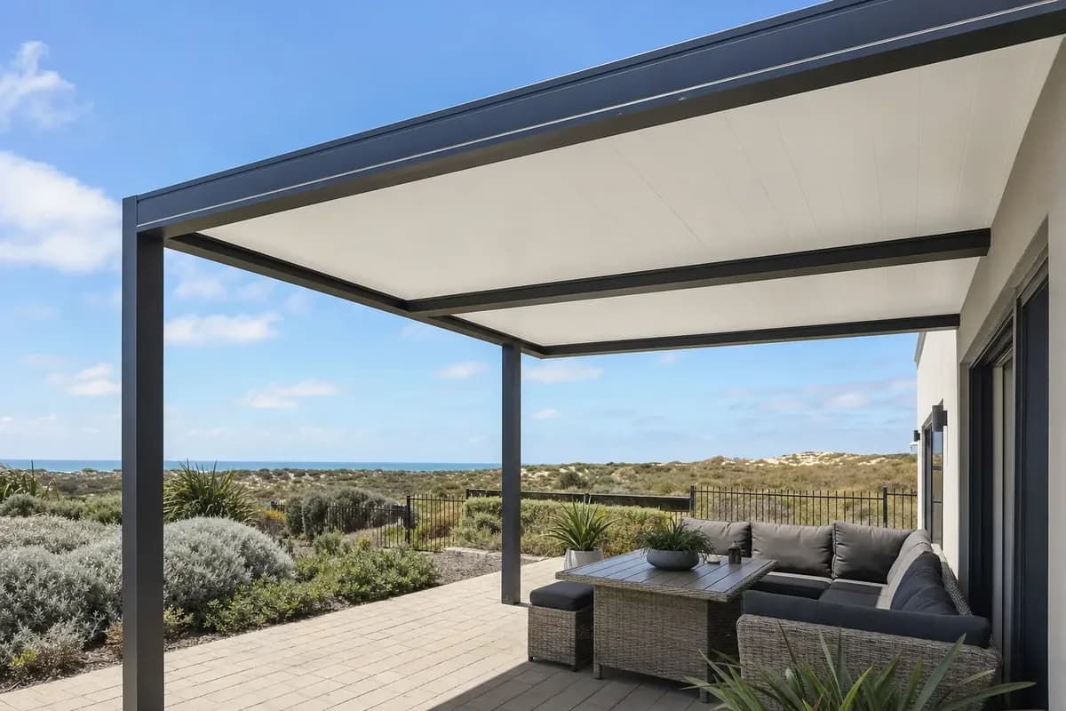 Charcoal steel patio with a white panel ceiling over an outdoor lounge looking out to coastal dunes and the ocean