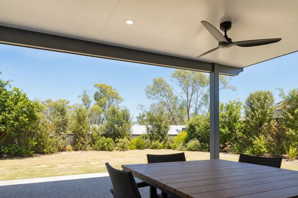 Insulated patio ceiling with a downlight and a black fan over an outdoor dining table on a sunny day