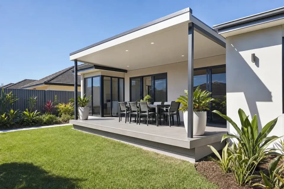 Skillion patio with a white steel ceiling over a raised paved platform and outdoor dining table
