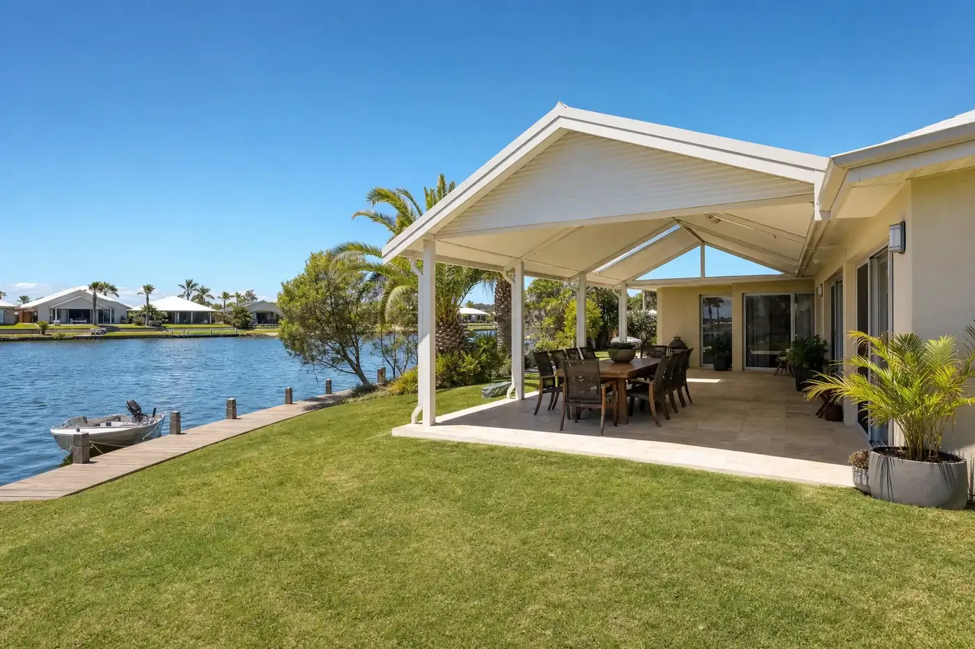 Gable patio with a white steel roof over a paved alfresco at a canal home