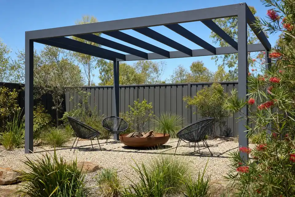 Grey steel pergola over a gravel fire pit area in a Perth backyard garden